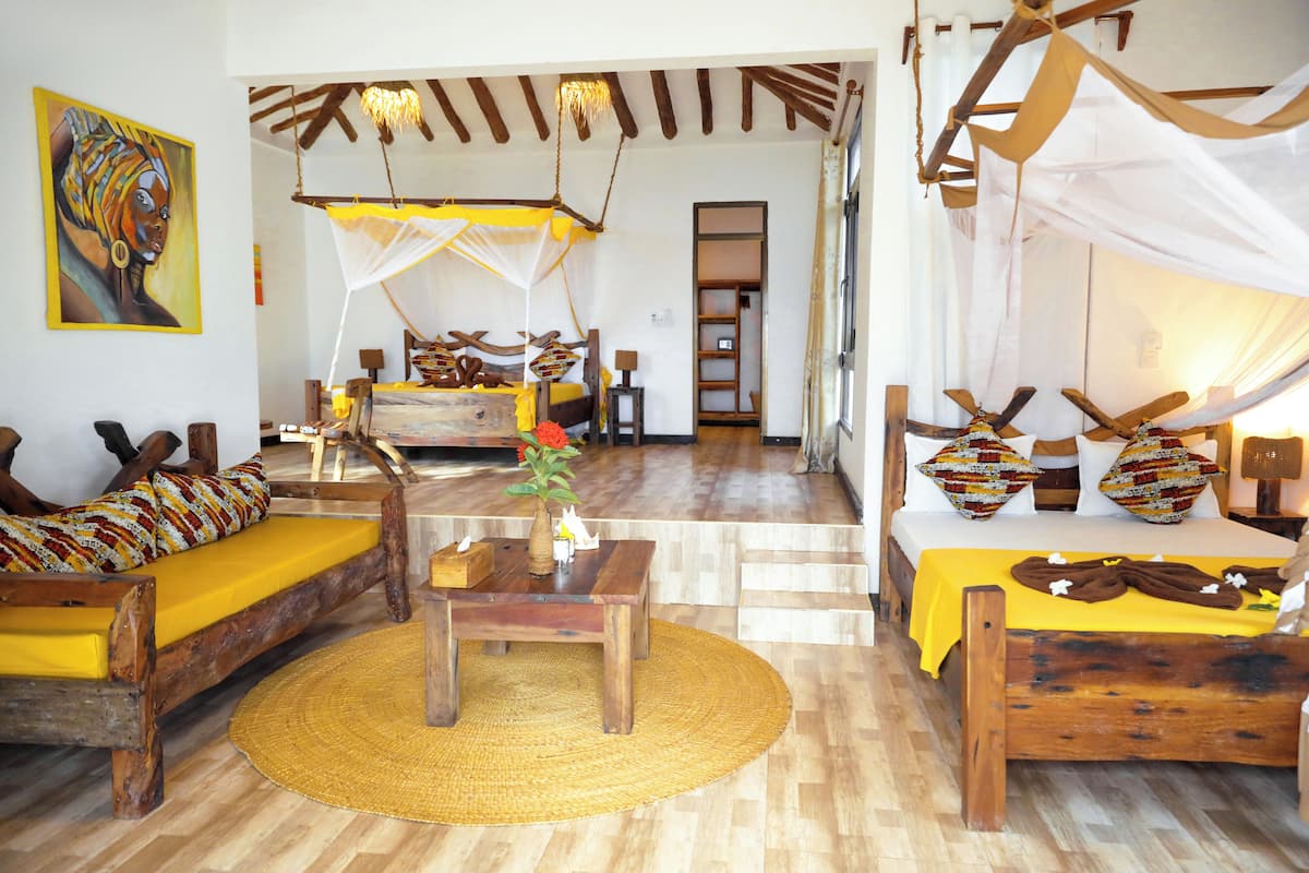 A room with a wooden bed, a sofa, a dining table, and a hanging chair.