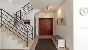 A staircase with a metal railing, a wooden door, a bench, and a wall-mounted clock. - Charming Villa Óbidos by LovelyStay (Nadadouro)