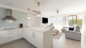 A modern kitchen with a central island, a dining area with a TV, and a living room with a sofa and a ceiling fan. - Charming Villa Óbidos by LovelyStay (Nadadouro)