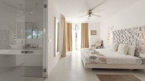 A modern bedroom with a large bed, a ceiling fan, and a view of the outdoors through a glass door. - Charming Villa Óbidos by LovelyStay (Nadadouro)
