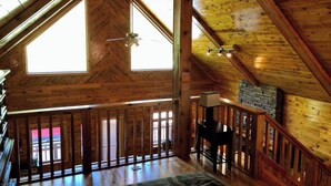 A wooden interior with a high ceiling, a staircase, and a view of the outside. - 15min to Pictured Rocks|Secluded Cabin w/Sauna (Wetmore)