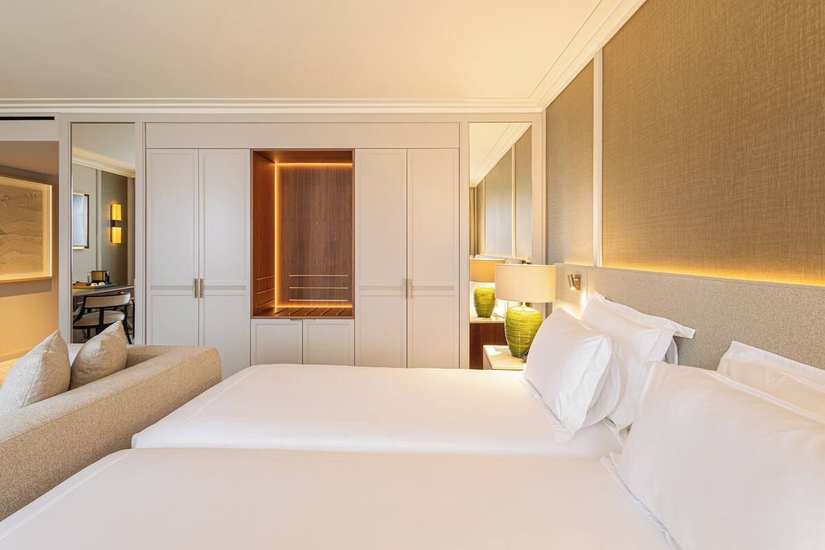 A hotel room with a large bed, a sofa, a desk, and a mirror.