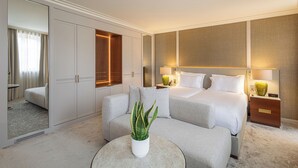 A modern hotel room with a large bed, a sofa, a small table with a plant, and a wardrobe. - Casa da Calçada Relais & Châteaux (Amarante)
