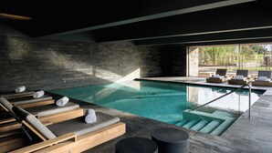 A modern indoor pool area with lounge chairs and a view of the outdoors. - Casa da Calçada Relais & Châteaux (Amarante)
