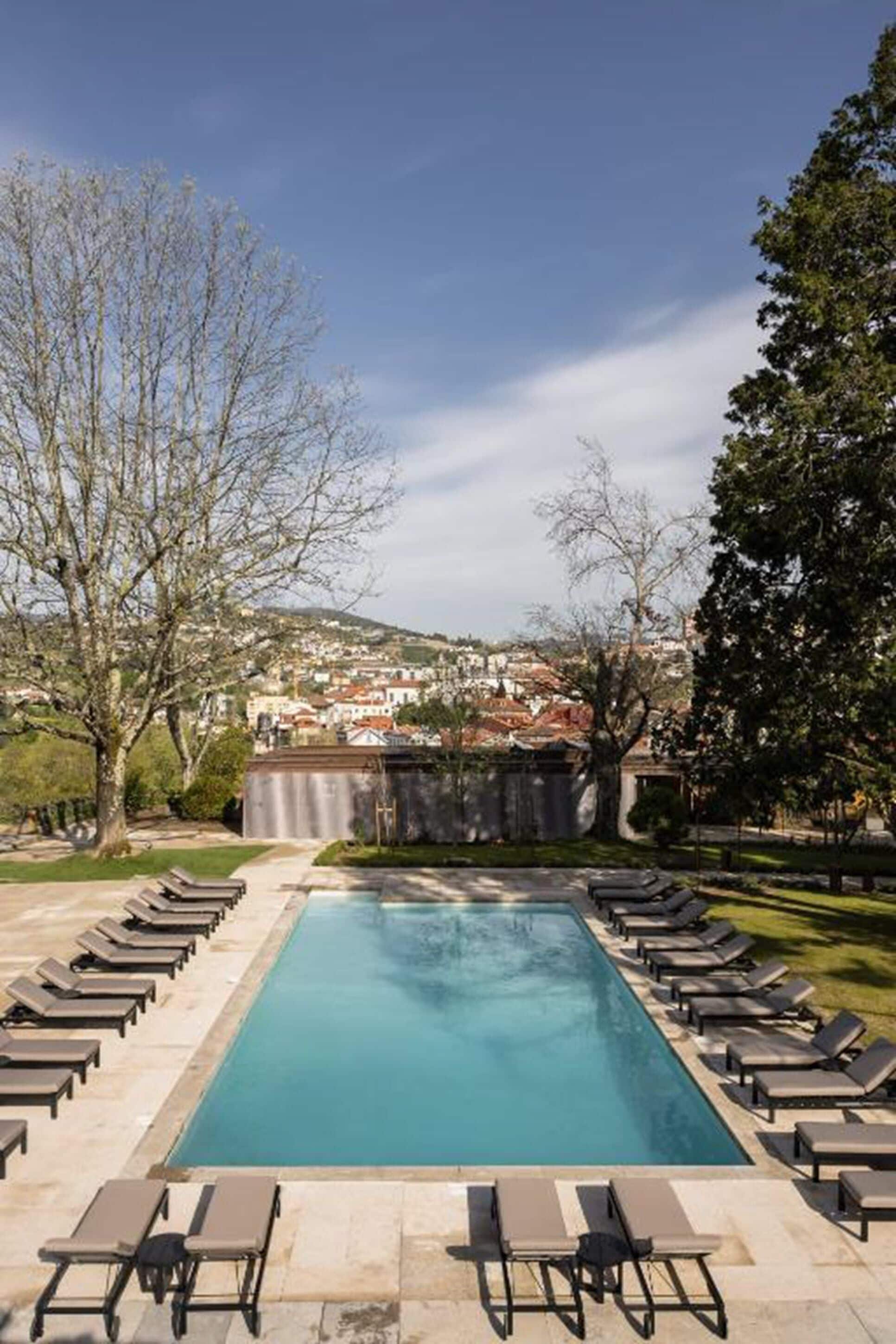 A swimming pool with lounge chairs and a view of a town in the background.