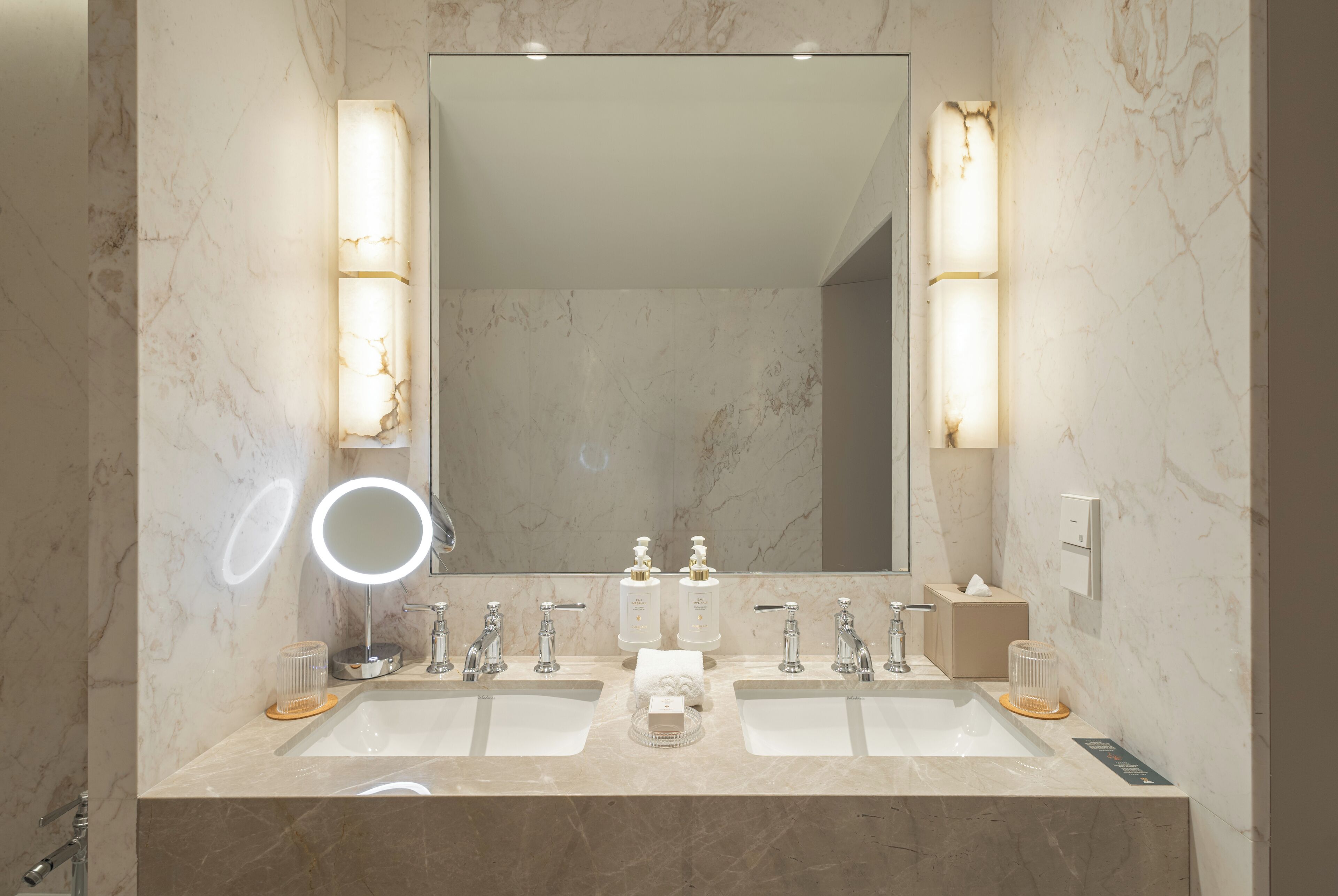 Ein Badezimmer mit zwei Waschbecken, einem großen Spiegel und einem beleuchteten Waschtisch.