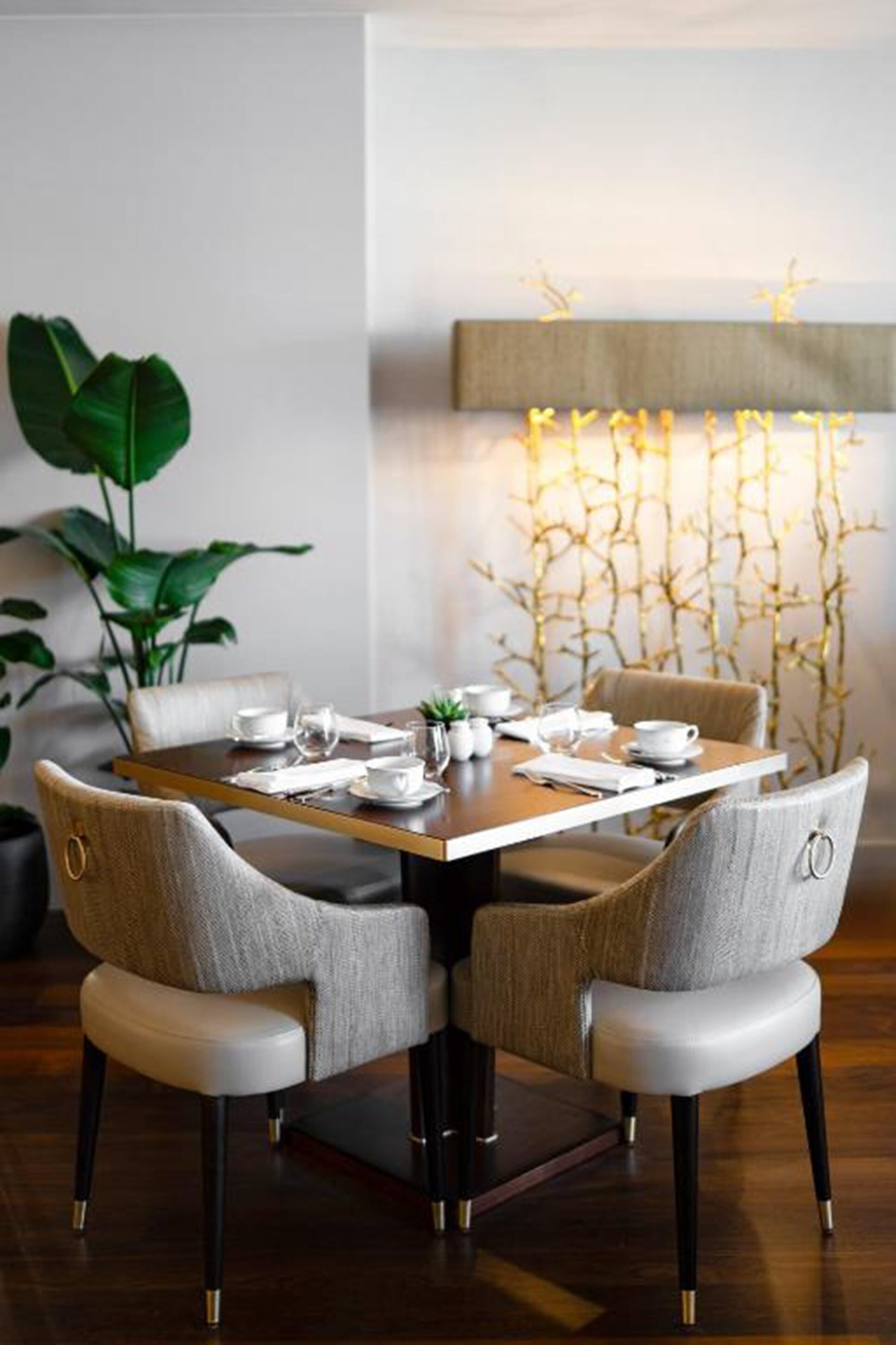 A dining area with a rectangular table set for four, surrounded by upholstered chairs with metallic legs.