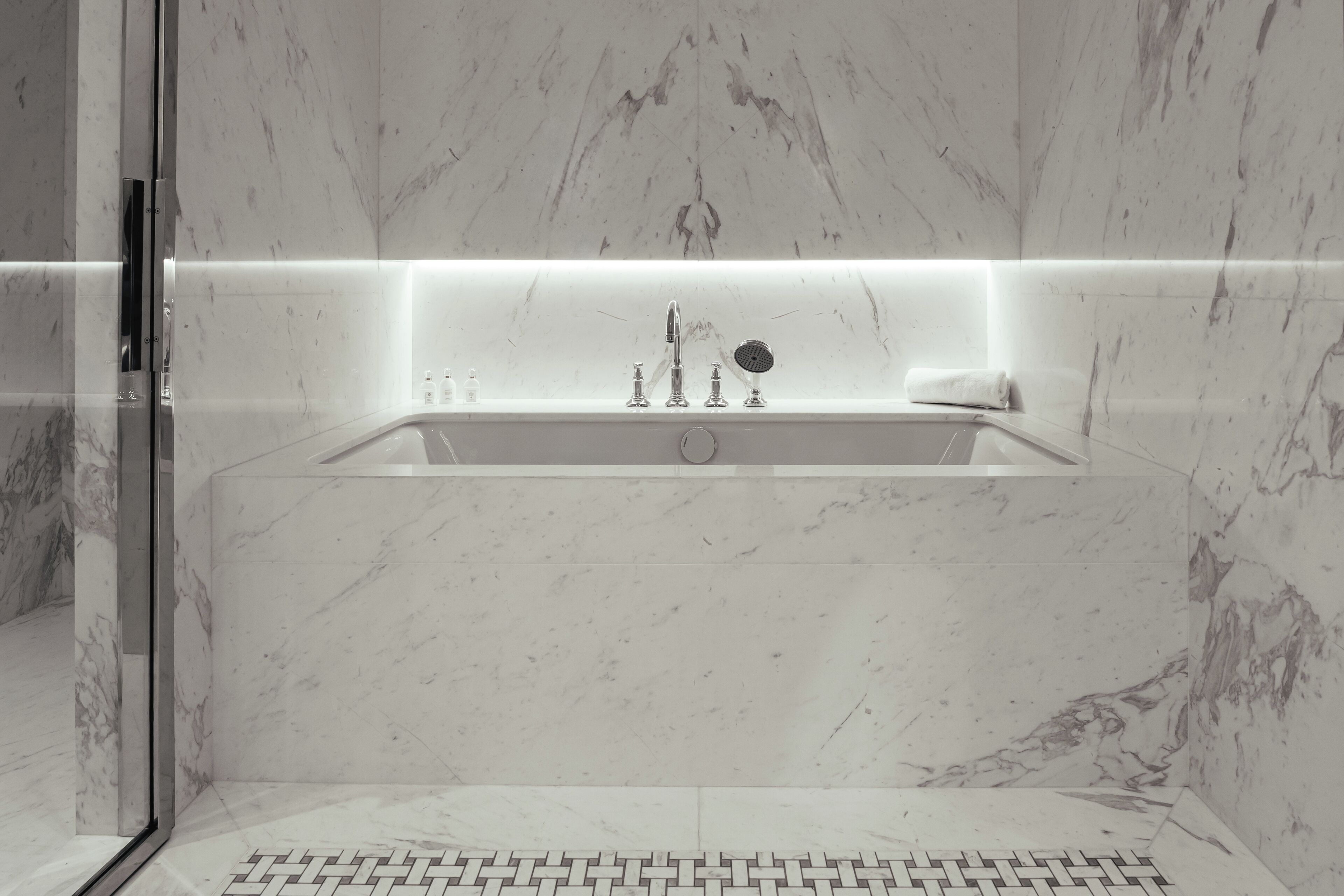 Une salle de bain moderne avec un lavabo en marbre, une douche en verre et un carrelage décoratif.