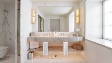 Een moderne badkamer met een grote spiegel, twee wasbakken en een weegschaal.