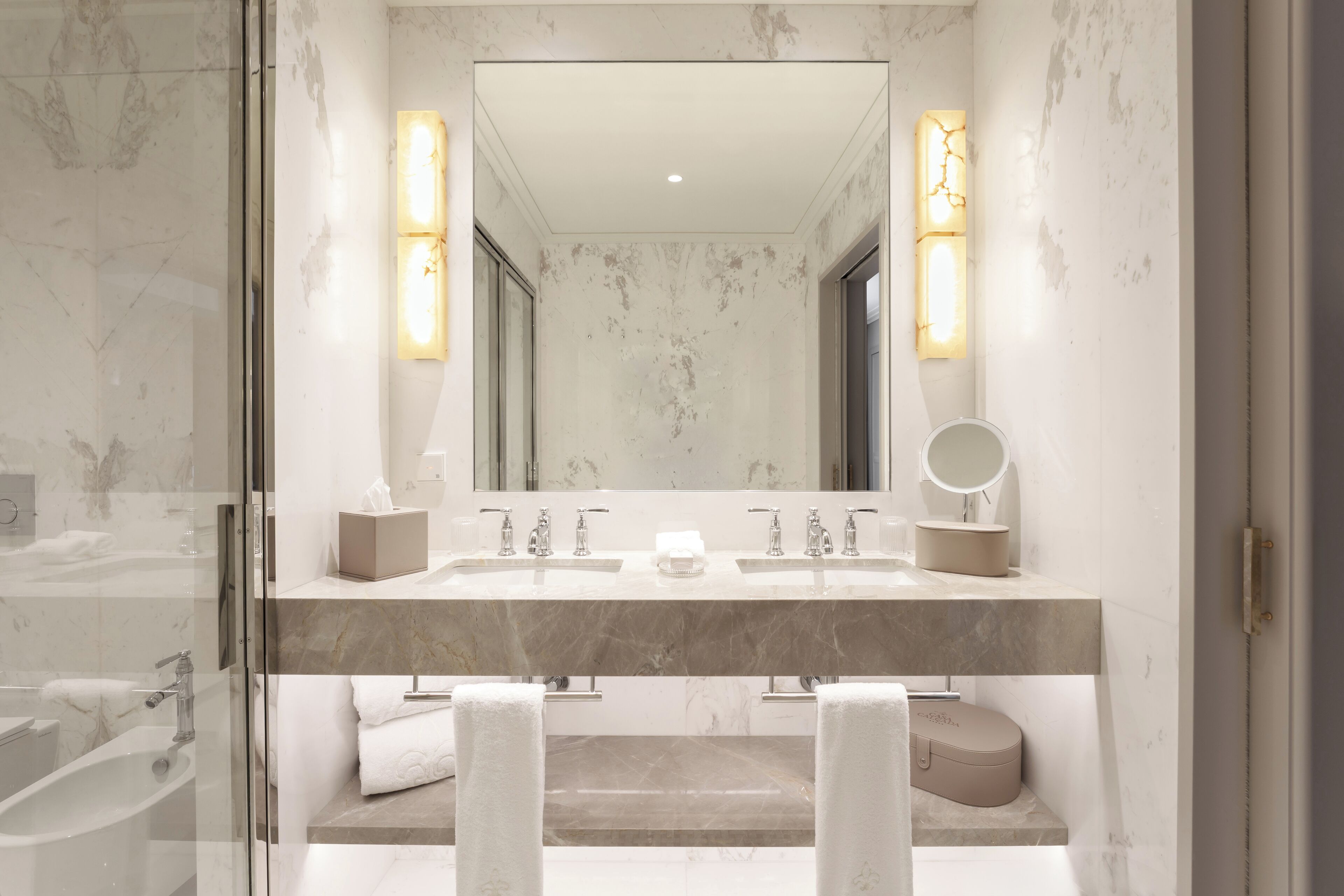 Une salle de bain moderne avec un grand miroir, deux lavabos, une baignoire et des toilettes.