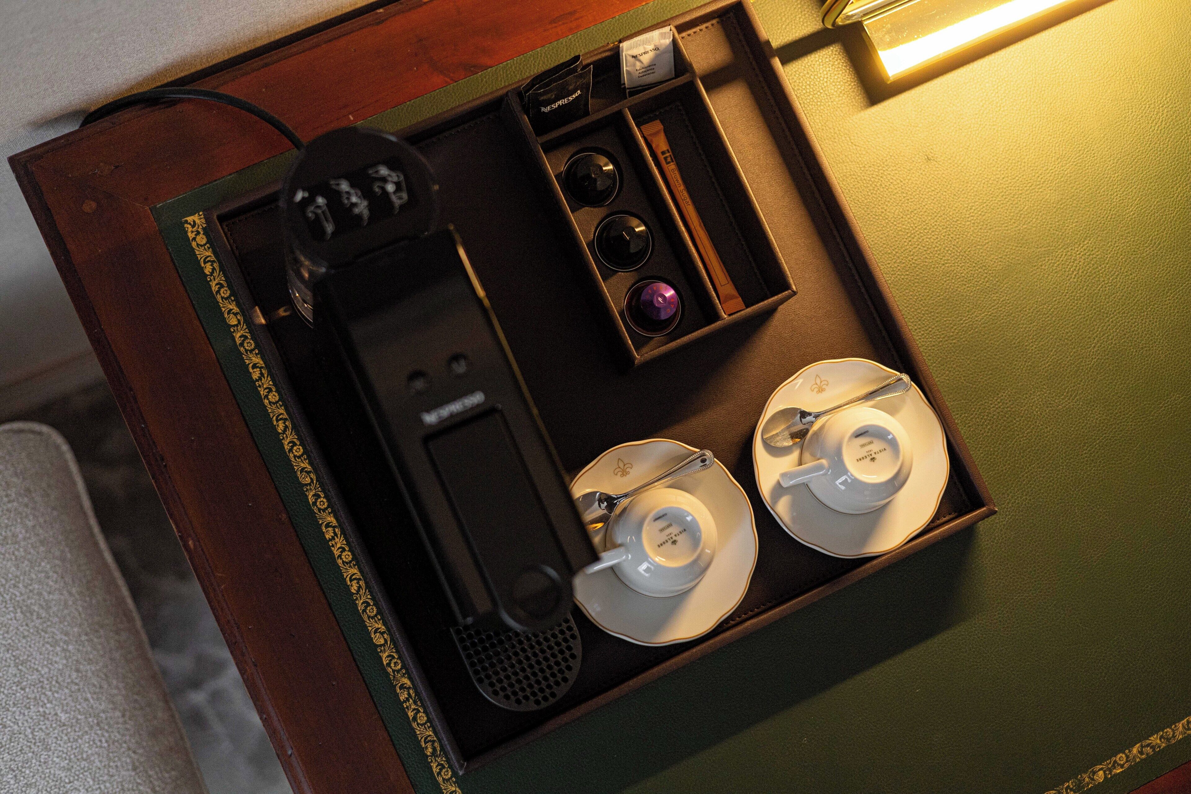 Una cafetera con un hervidor de agua y dos tazas en una caja de madera.