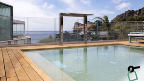 A modern outdoor swimming pool with a wooden deck, a glass enclosure, and a view of the sea and mountains. - Hotiday Room Collection - Nerano (Marina del Cantone)