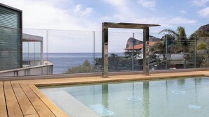 A modern outdoor swimming pool with a wooden deck, a glass enclosure, and a view of the sea and mountains. - Hotiday Room Collection - Nerano (Marina del Cantone)
