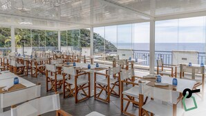 A spacious outdoor dining area with tables and chairs, large windows offering views of the sea and hills. - Hotiday Room Collection - Nerano (Marina del Cantone)