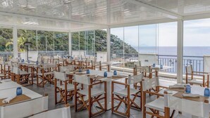 A spacious outdoor dining area with tables and chairs, large windows offering views of the sea and hills. - Hotiday Room Collection - Nerano (Marina del Cantone)