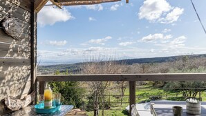 A wooden deck with a table, a bottle of orange juice, and glasses. - Comfortable nature gîte with swimming pool, ideal for 2 people, pet-friendly (Salazac)