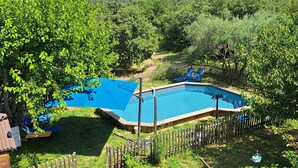 A rectangular swimming pool surrounded by a wooden fence, with a view of a forested area and a distant mountain. - Comfortable nature gîte with swimming pool, ideal for 2 people, pet-friendly (Salazac)