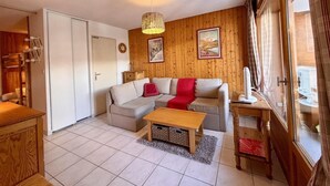 Un salon chaleureux avec un canapé, une table basse, un meuble en bois et une fenêtre avec des rideaux.