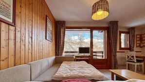 Une pièce confortable avec des murs en bois, un lit, un bureau et une chaise.
