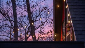 A balcony with string lights against a twilight sky.