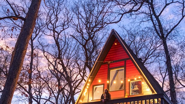 A cabin with a wooden deck, large windows, and a balcony.