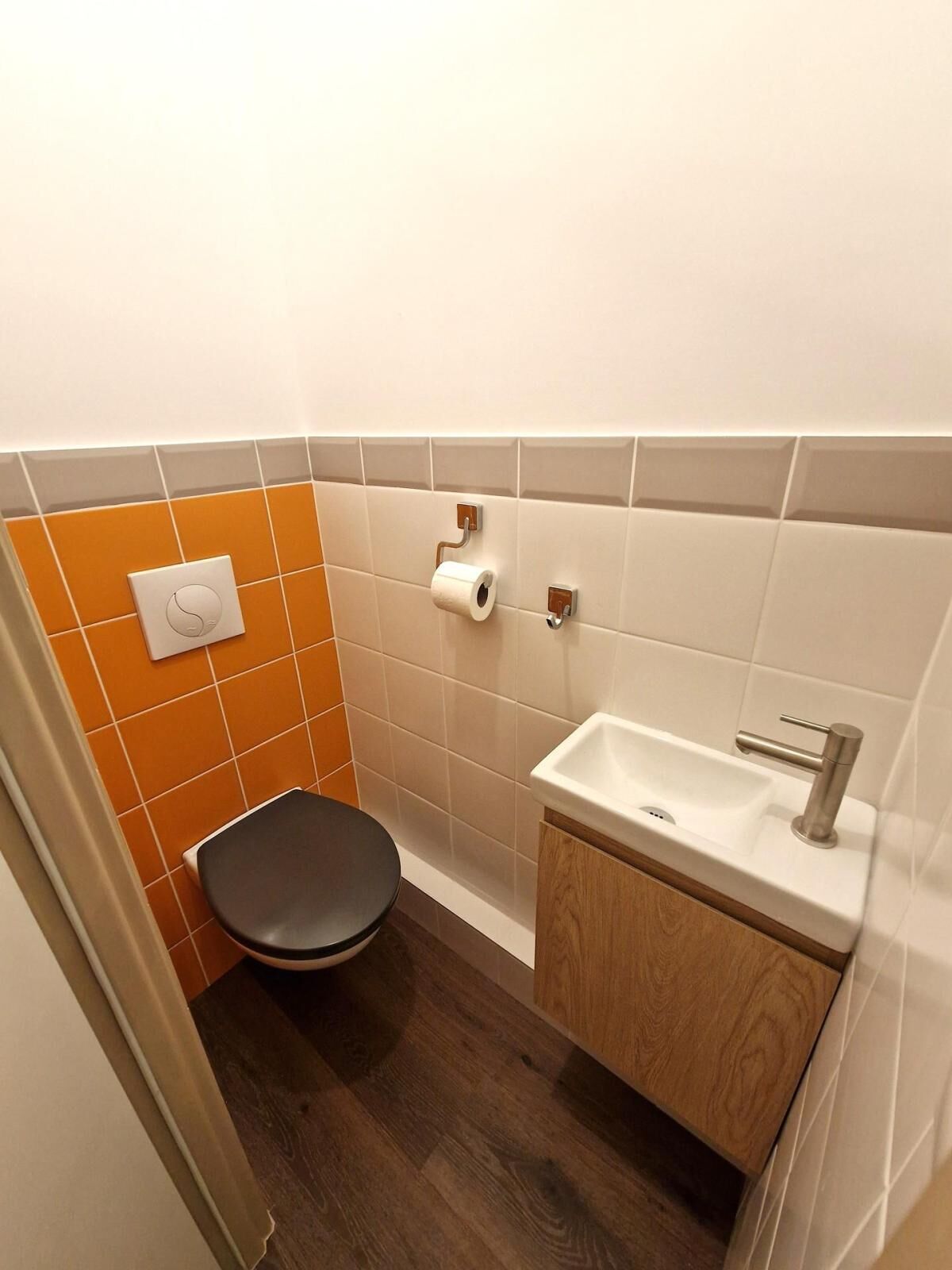 A small bathroom with a toilet, a sink, and a toilet paper holder.