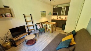 A compact living space with a sofa, a coffee table, a TV, a dining table with chairs, and a kitchen area. - Ski-in/ski-out & foot of the slopes, 3rd floor, view ski slopes, balcony, tv, ski locker, 28m² (Valfréjus)