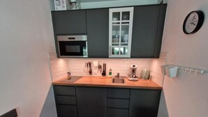 A compact kitchen with dark cabinets, a wooden countertop, a built-in oven, a sink, and a clock on the wall. - Ski-in/ski-out & foot of the slopes, 3rd floor, view ski slopes, balcony, tv, ski locker, 28m² (Valfréjus)