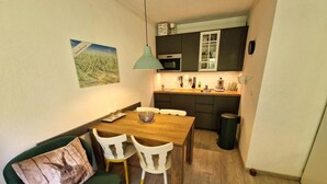 A compact kitchen with a dining area, a green sofa, and a small table with chairs. - Ski-in/ski-out & foot of the slopes, 3rd floor, view ski slopes, balcony, tv, ski locker, 28m² (Valfréjus)