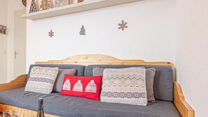A cozy room with a wooden headboard sofa, a bottle of wine, and a wooden table. - 100m from ski slopes, Ground floor, terrace, ski locker, 40m², Valfréjus (Valfréjus)