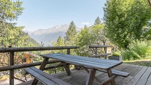A wooden deck with picnic tables and a railing overlooking a mountainous landscape. - 100m from ski slopes, Ground floor, terrace, ski locker, 40m², Valfréjus (Valfréjus)