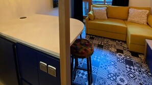 A compact living space with a kitchenette, a sofa, and a patterned floor. - 30m from ski slopes, 4th floor, balcony, tv, ski locker, 19m², Valfréjus (Valfréjus)