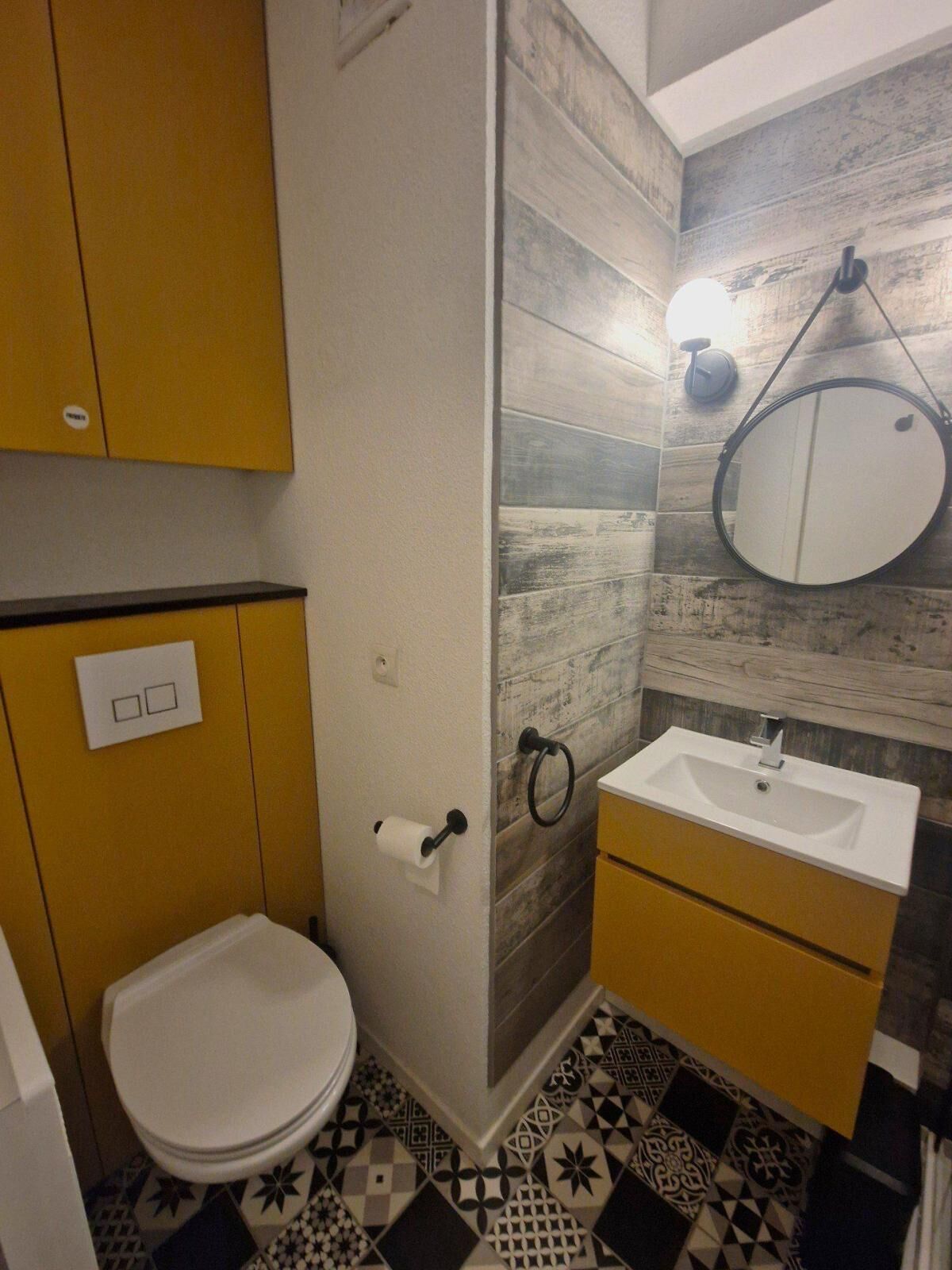 A bathroom with a toilet, sink, and mirror.