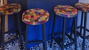 A bar area with a white countertop, three stools with colorful woven seats, a large wall clock, and pendant lighting. - 30m from ski slopes, 4th floor, balcony, tv, ski locker, 19m², Valfréjus (Valfréjus)