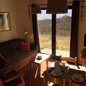 Uma sala de estar acolhedora com um sofá, uma mesa de centro e um espaço de jantar com uma mesa posta para refeição.