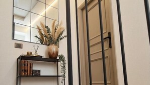 A modern staircase with a wooden finish, a black metal railing, and a wall-mounted console table with a mirror, books, and a vase with dried plants. - WelcHome Vitorchiano double room with balcony  (Vitorchiano)