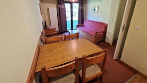 A dining area with a wooden table and chairs, a sofa, and a door leading to another room. - Ski-in/ski-out & foot of the slopes, Ground floor, view mountain, terrace, balcony, tv, ski locker (Valfréjus)