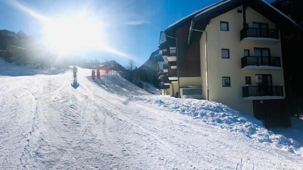 A snow-covered ski slope with a building featuring balconies and a clear sky. - Ski-in/ski-out & foot of the slopes, Ground floor, view mountain, terrace, balcony, tv, ski locker (Valfréjus)