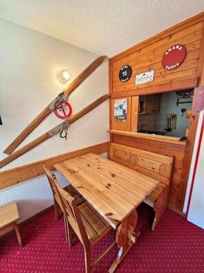 Eine Holzbank und ein Holztisch in einer Ecke, eine Holzwand, ein Schild mit der Nummer 70 und ein Poster an der Wand.