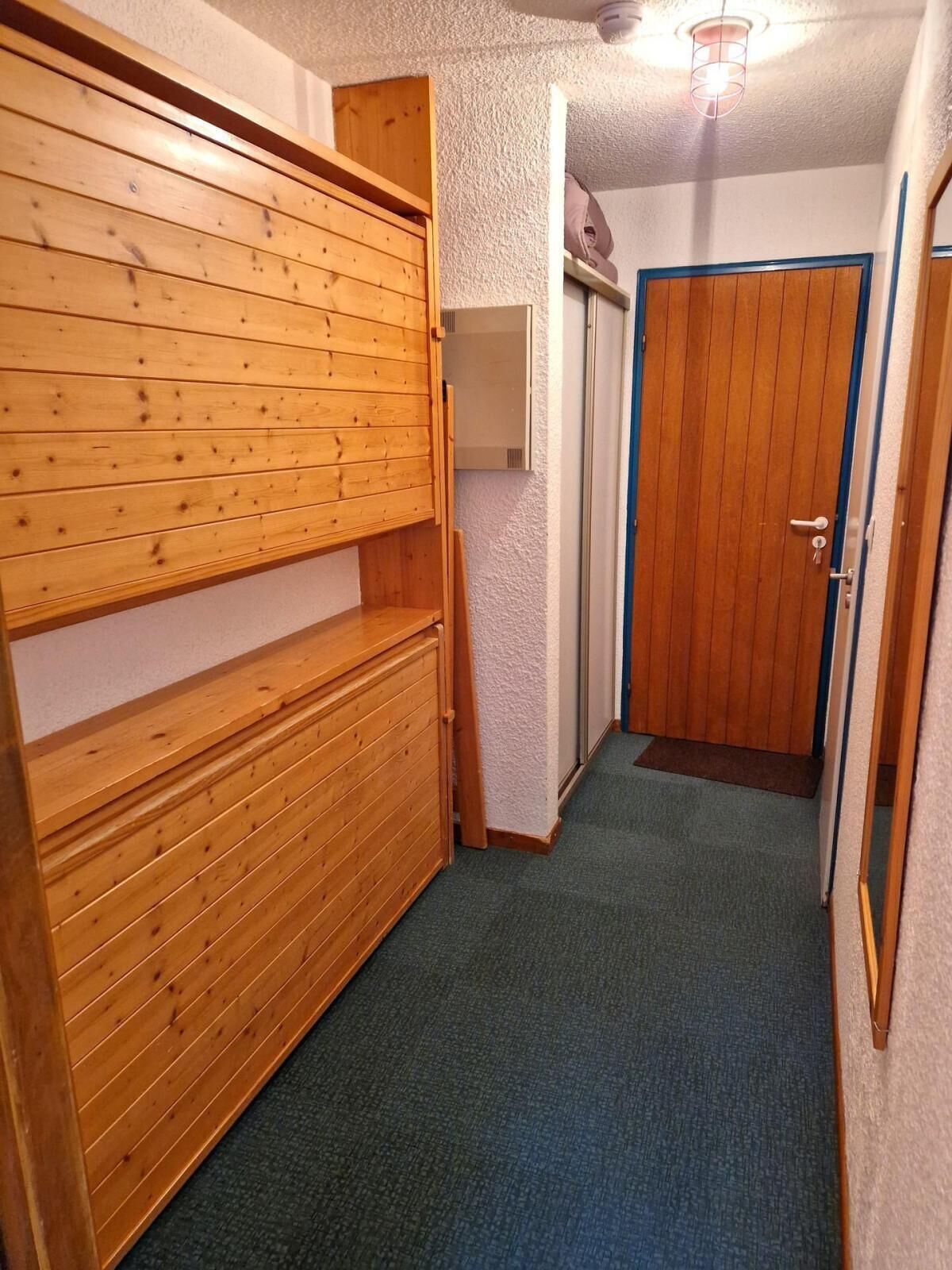 A hallway with a wooden bench, a door, and a ceiling light fixture.
