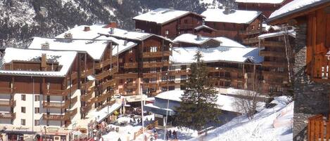 A ski resort with multi-story wooden buildings, ski slopes, and a mountainous backdrop.