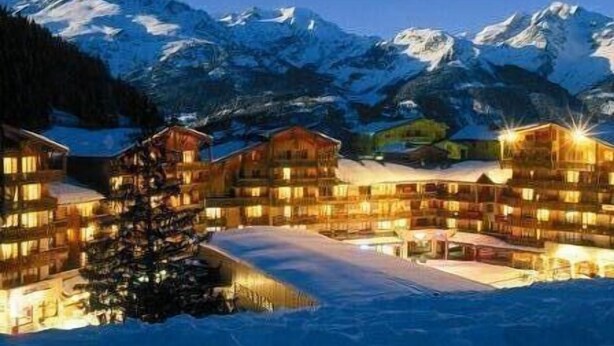 Un hôtel à plusieurs étages doté d’une cour enneigée et offrant une vue sur les montagnes.