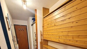 Un couloir étroit, avec un lit superposé en bois sur le côté droit, une porte en bois au fond et un luminaire au plafond.