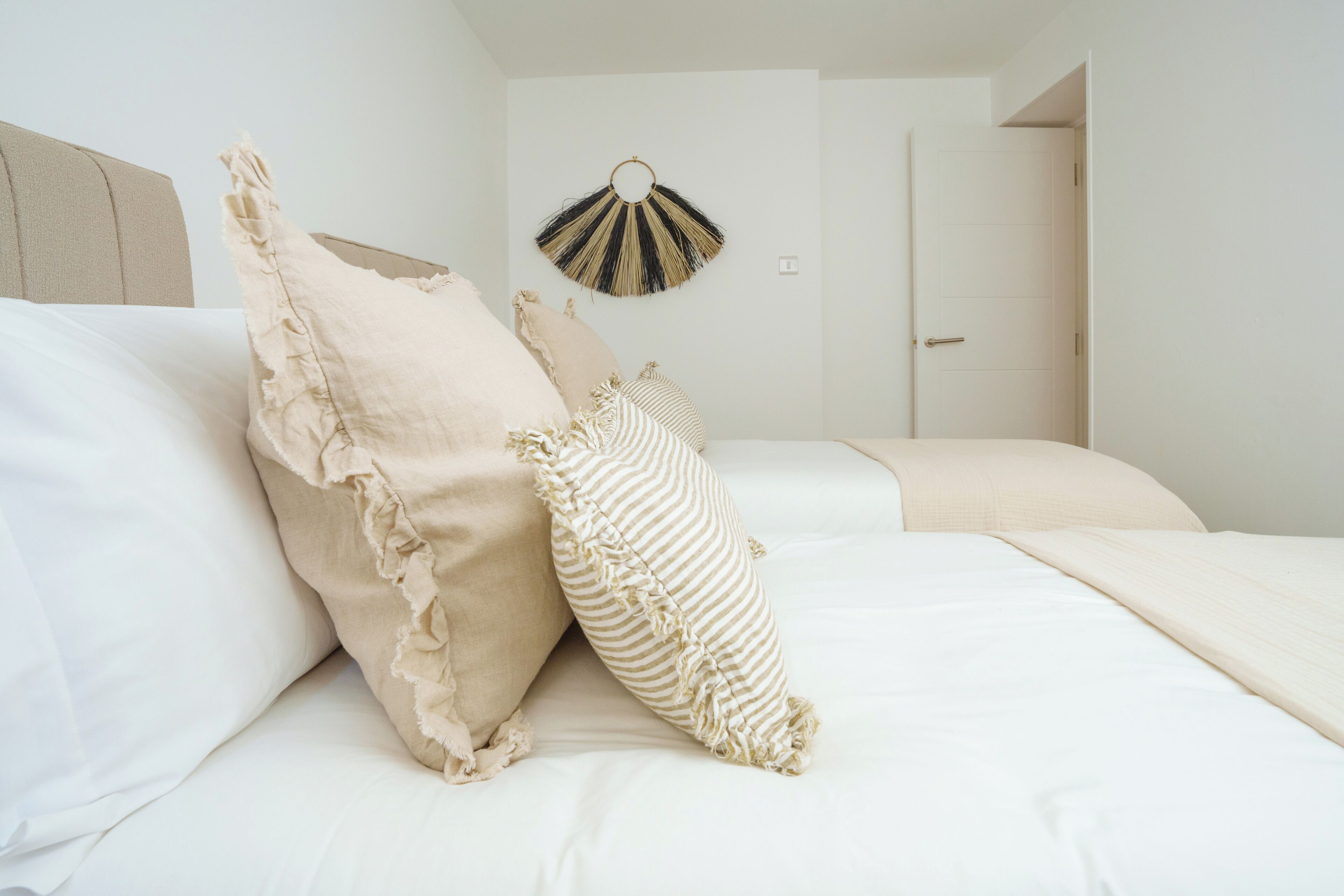 Une chambre à coucher avec un lit, des oreillers et un objet décoratif fixé au mur.
