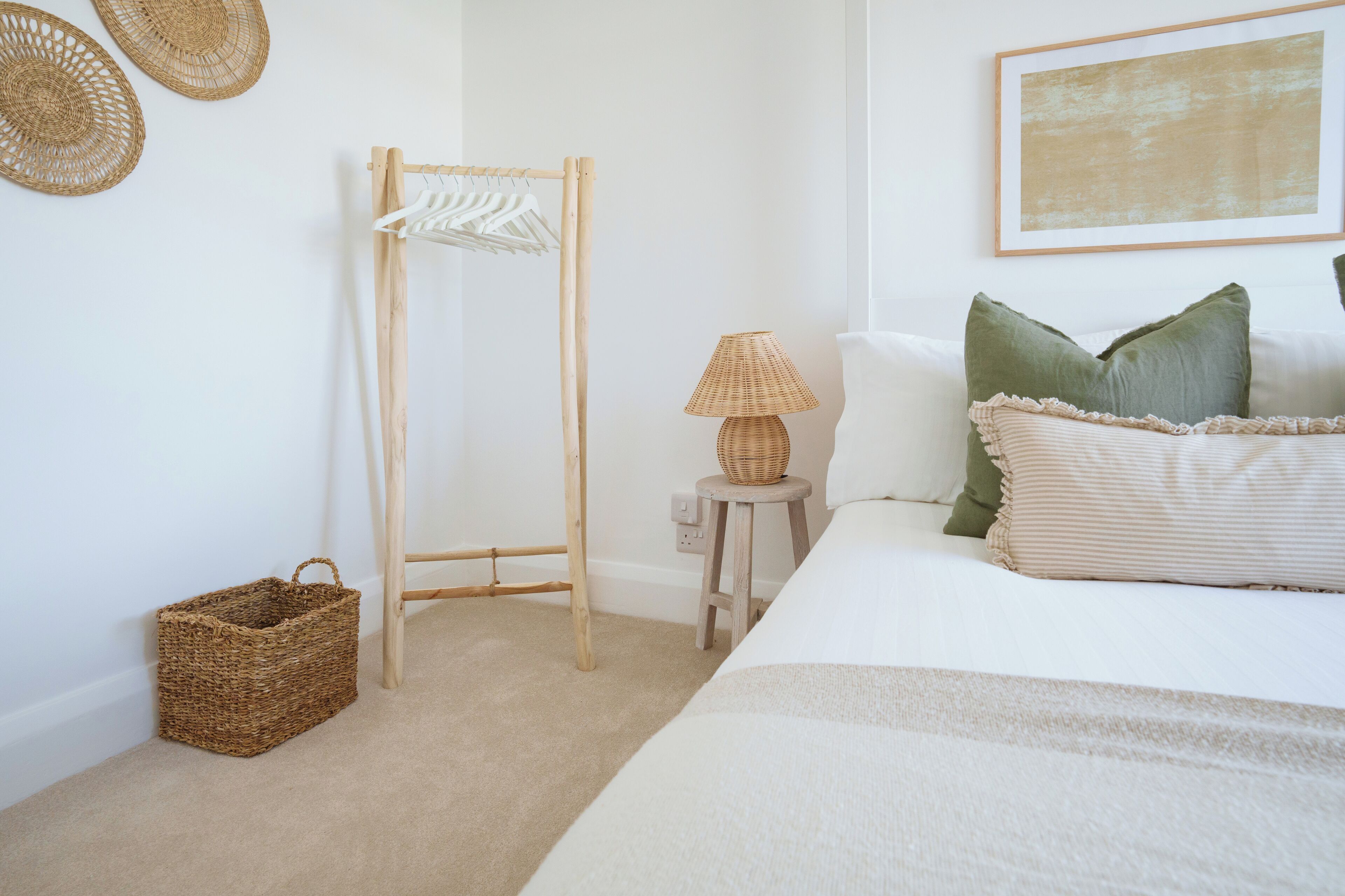 A bedroom with a bed, a wooden drying rack, a lamp, and a woven basket.
