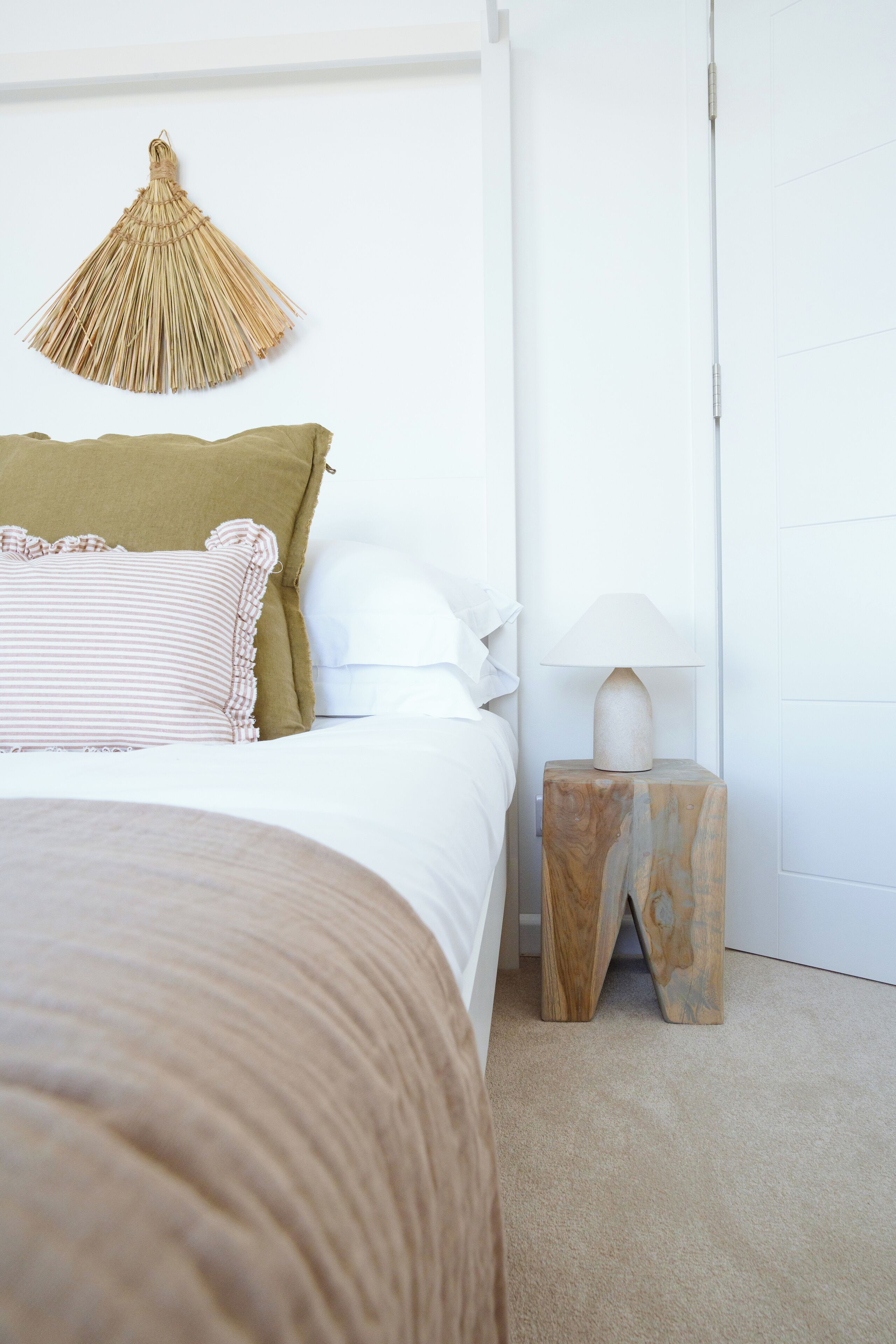 Un dormitorio con cama, almohadas, una lámpara colgante y una mesita de noche.