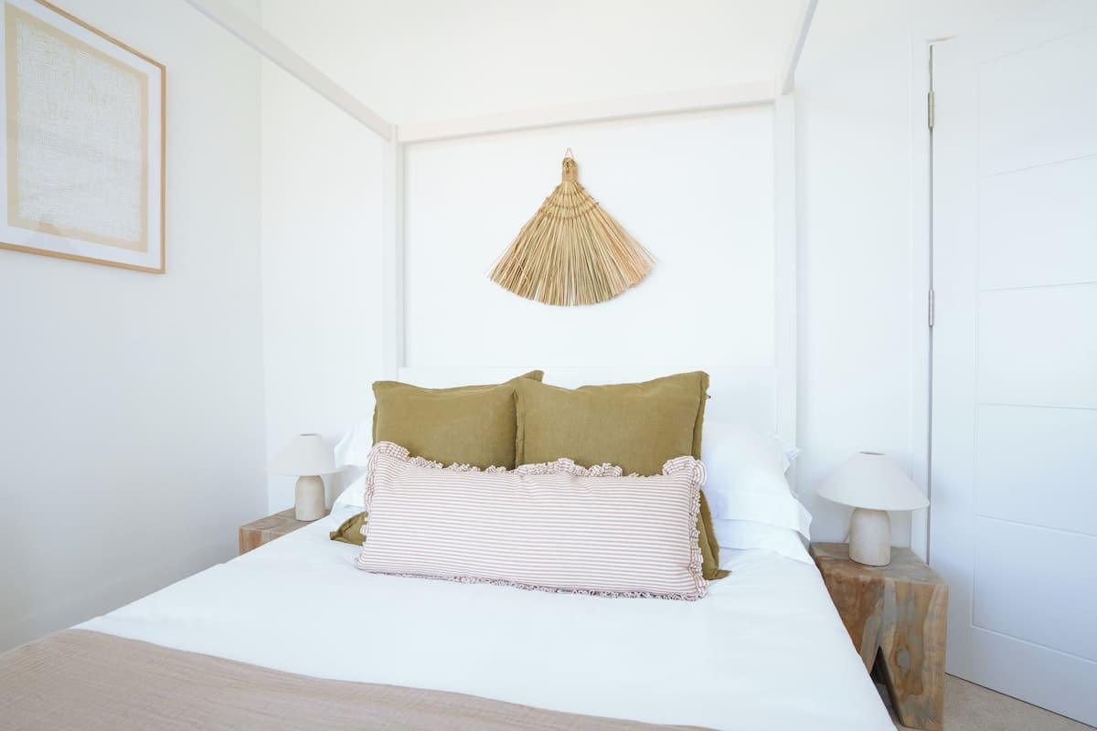 A neatly made bed with two pillows, a bedside lamp, and a wall-mounted hanging light fixture.