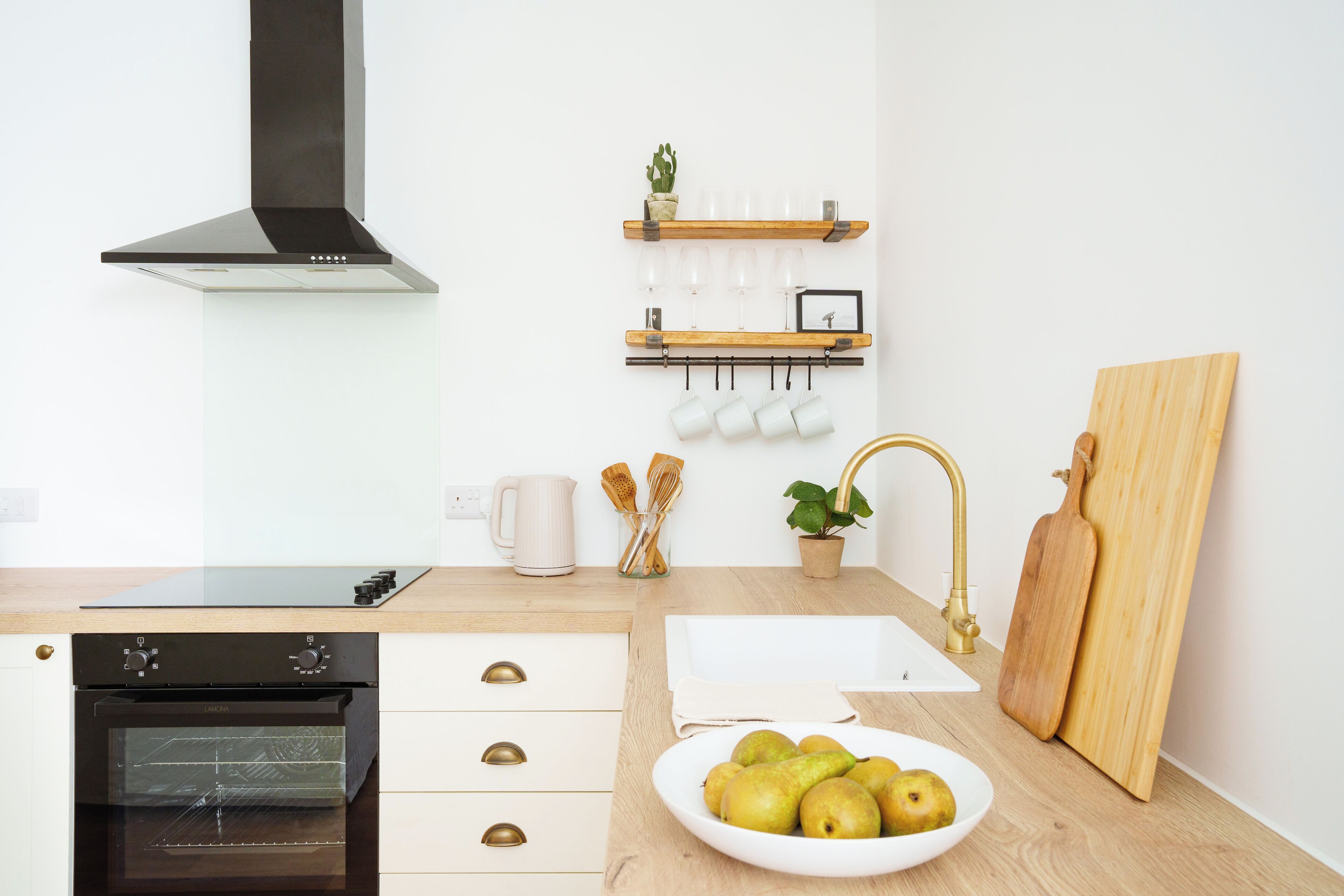 A modern kitchen with a built-in oven, a sink, and a wooden countertop.