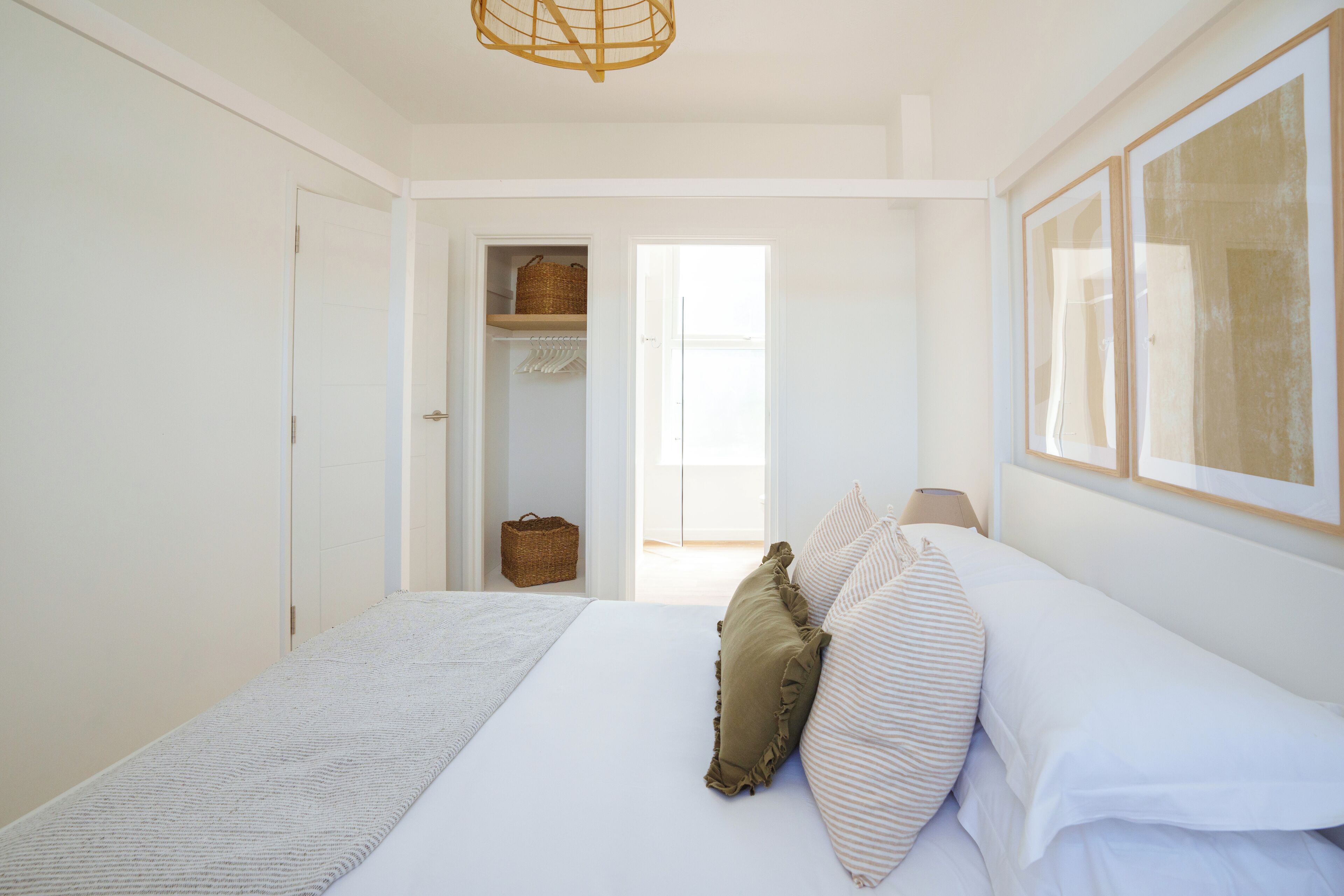 A bedroom with a bed, a wardrobe, a door leading to a balcony, and a hanging light fixture.