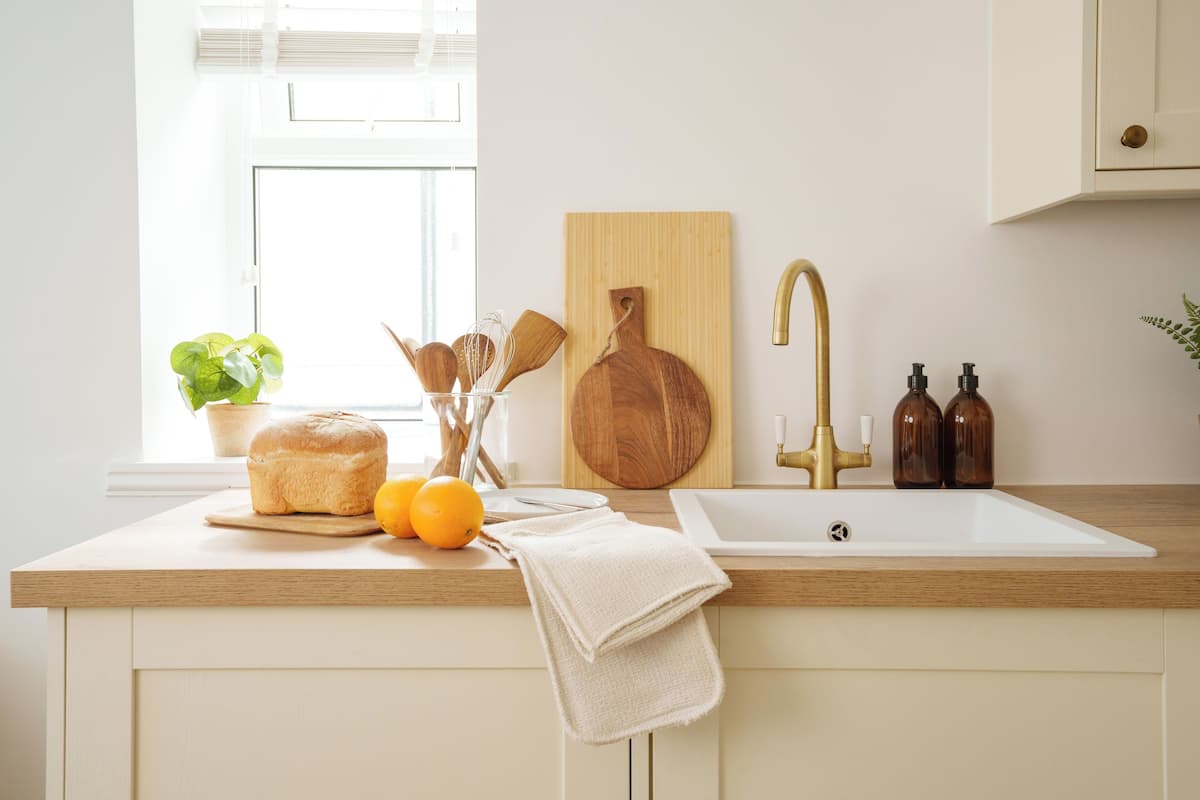 A kitchen with a wooden countertop, a sink, a cutting board, and a potted plant.